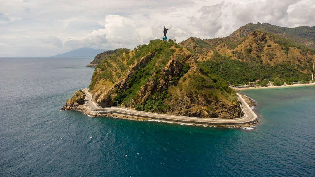 Paisagem costeira de Díli com estátua sobre uma colina